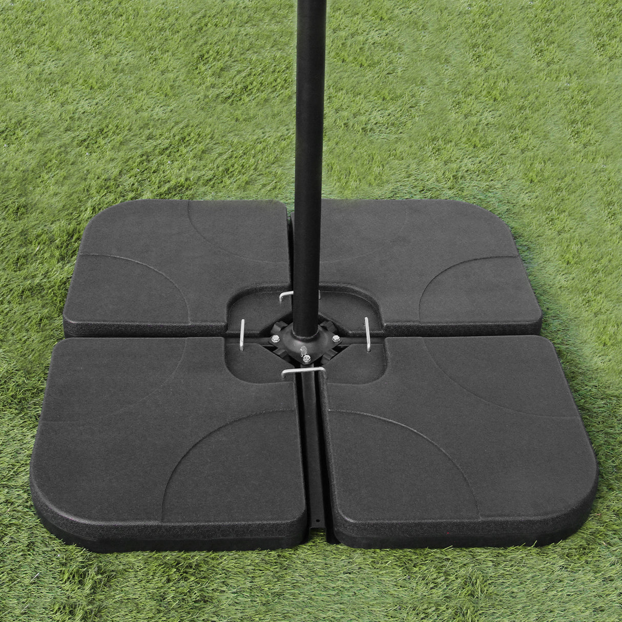 Base preta sólida para guarda-sol, com quatro peças quadradas, ideal para estabilidade em áreas externas, sobre grama verde