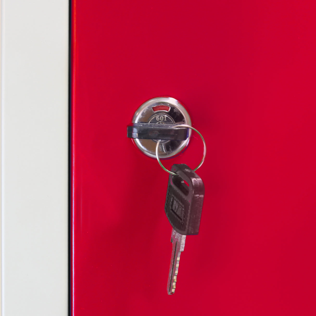 Fechadura prateada com chave pendurada em armário de metal vermelho, destacando a superfície lisa e vibrante do material