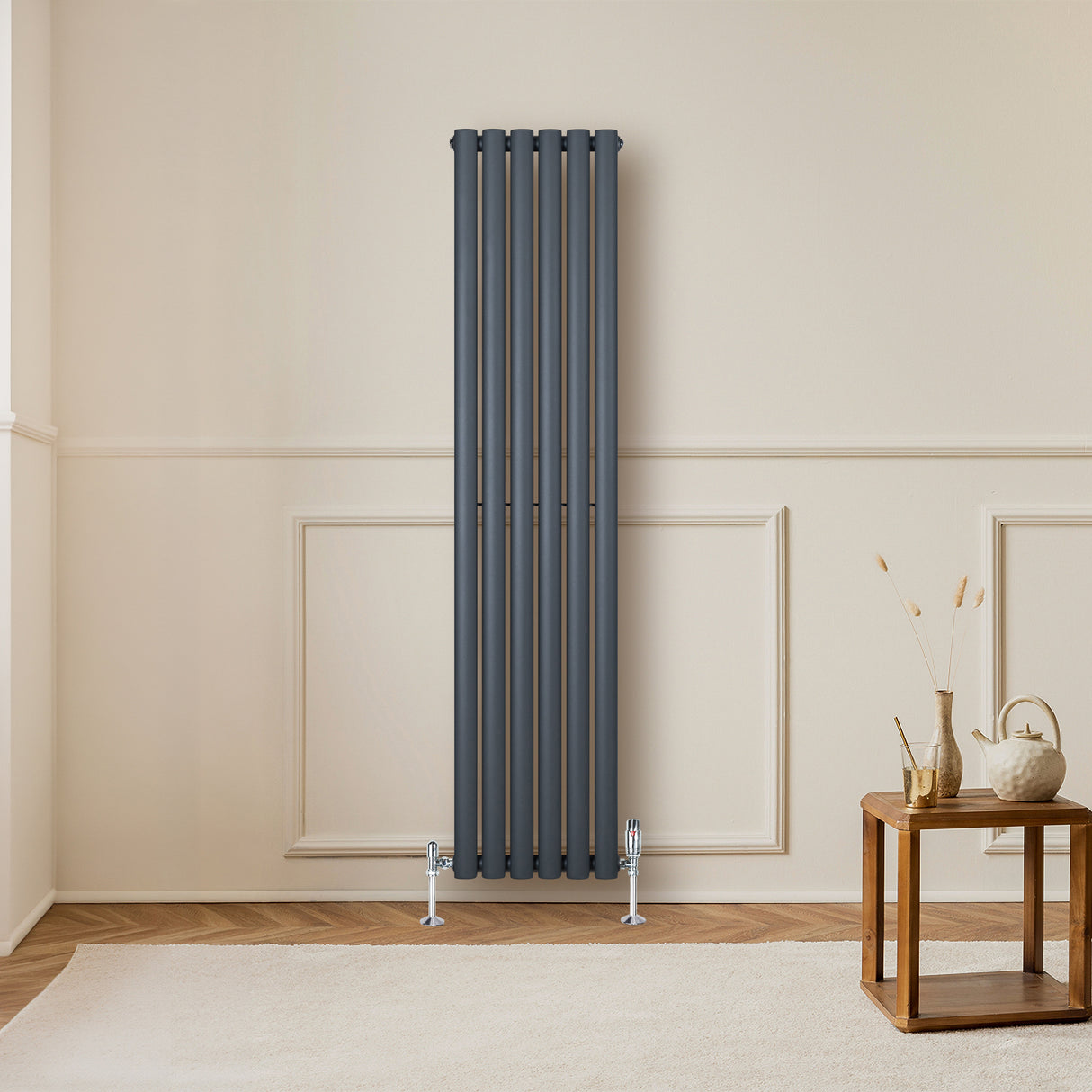 Radiador de coluna simples oval cinza antracite, com design elegante e moderno, instalado em parede clara, ao lado de mesa de madeira