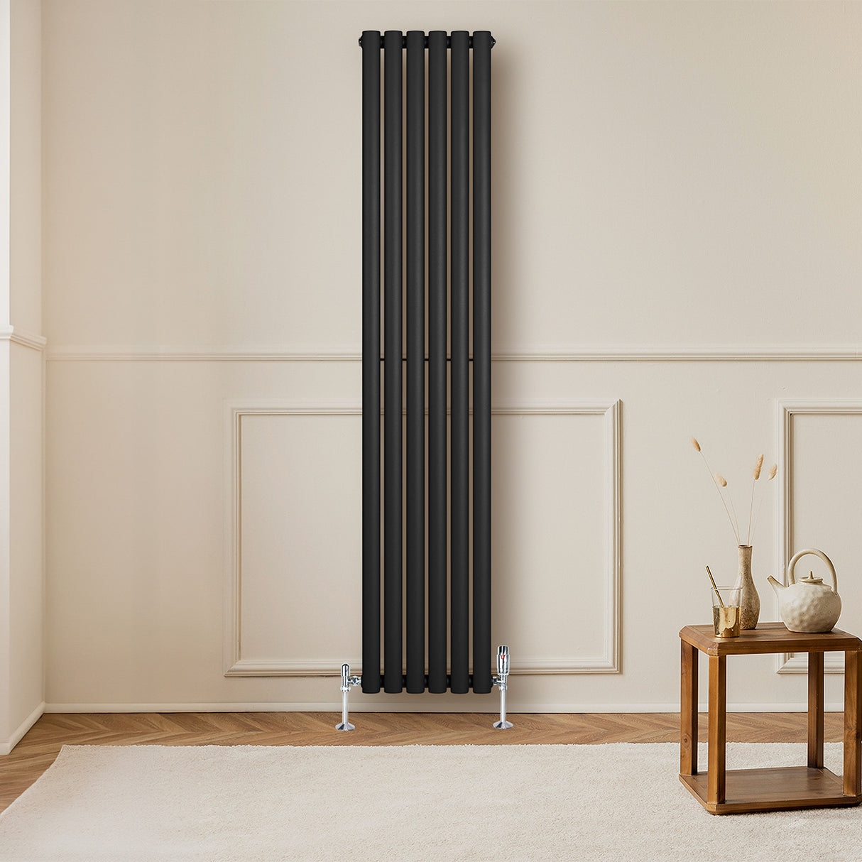 Radiador de coluna simples oval preto, com válvulas, instalado em parede clara, ao lado de mesa de madeira e decoração minimalista