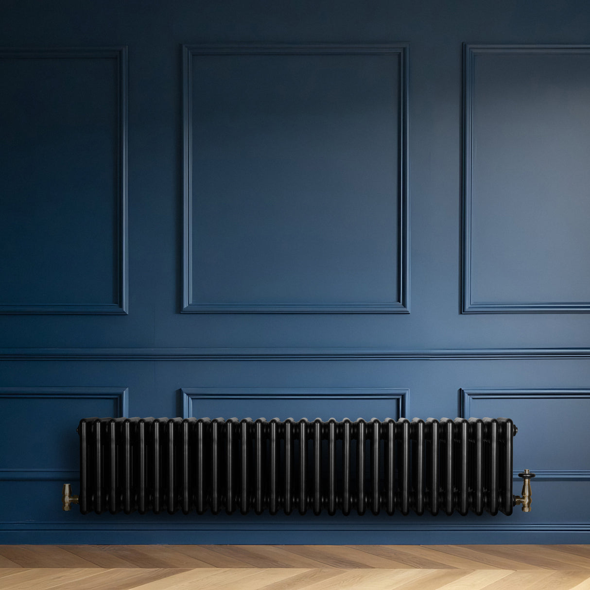Radiador tradicional de 4 colunas, acabamento preto brilhante, instalado em parede azul, com válvulas de metal dourado visíveis
