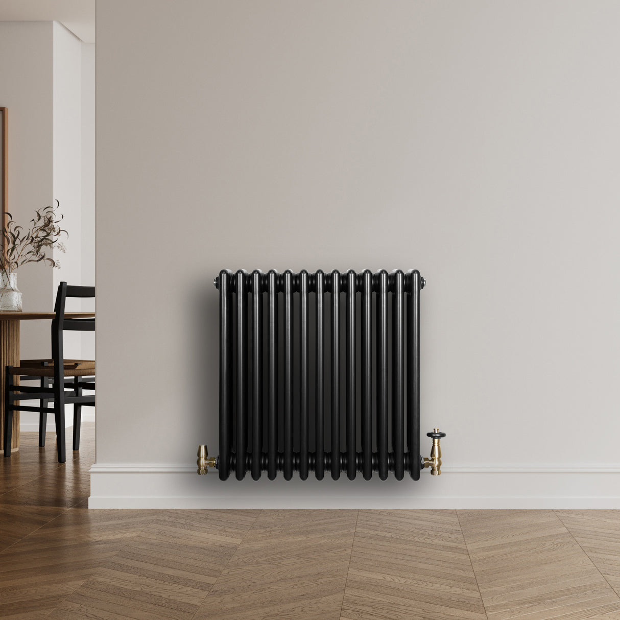 Radiador tradicional de 4 colunas em preto, com válvulas douradas, instalado em parede clara, destacando seu design elegante e moderno