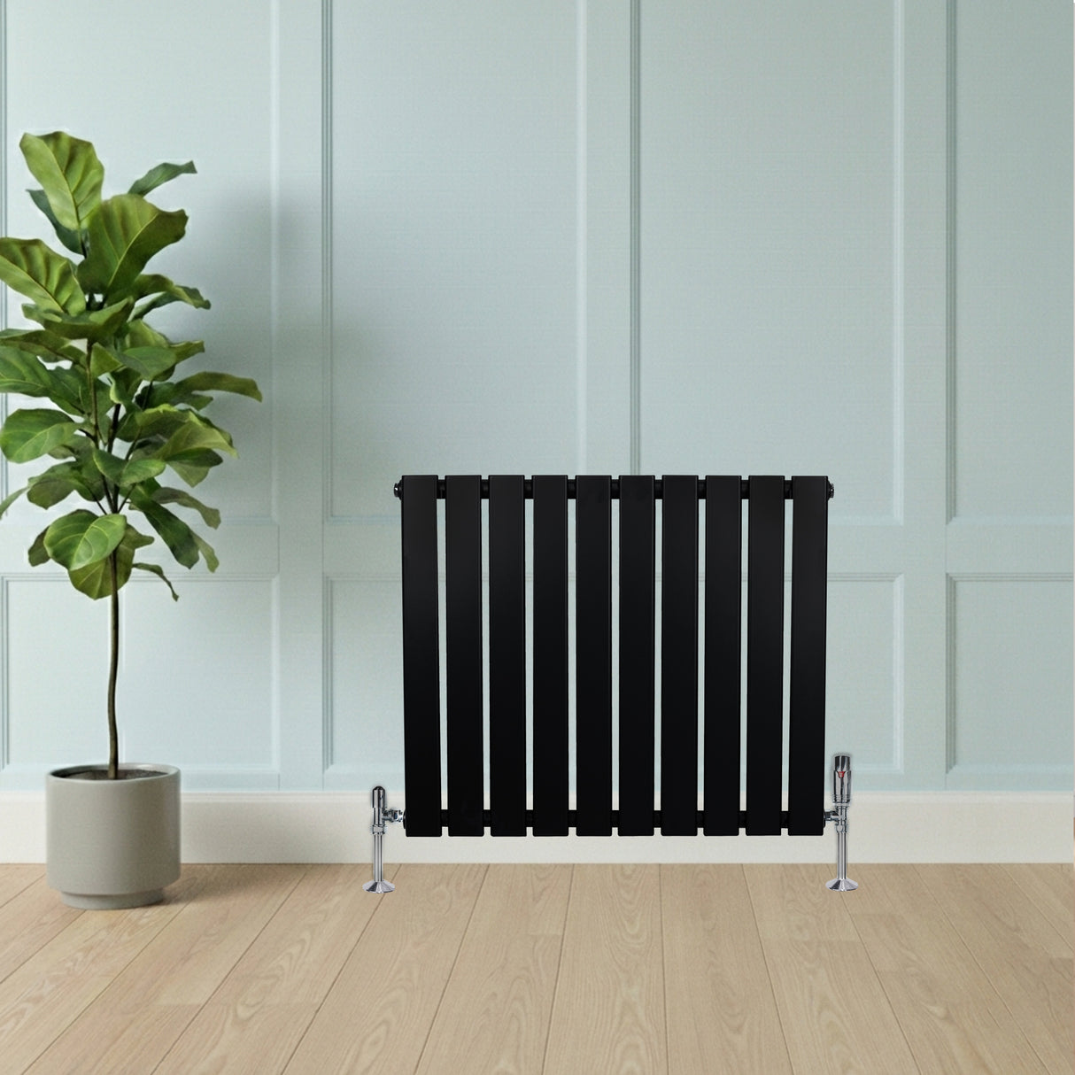 Radiador de coluna única preto, com design moderno e listras verticais, instalado em parede clara, ao lado de planta em vaso