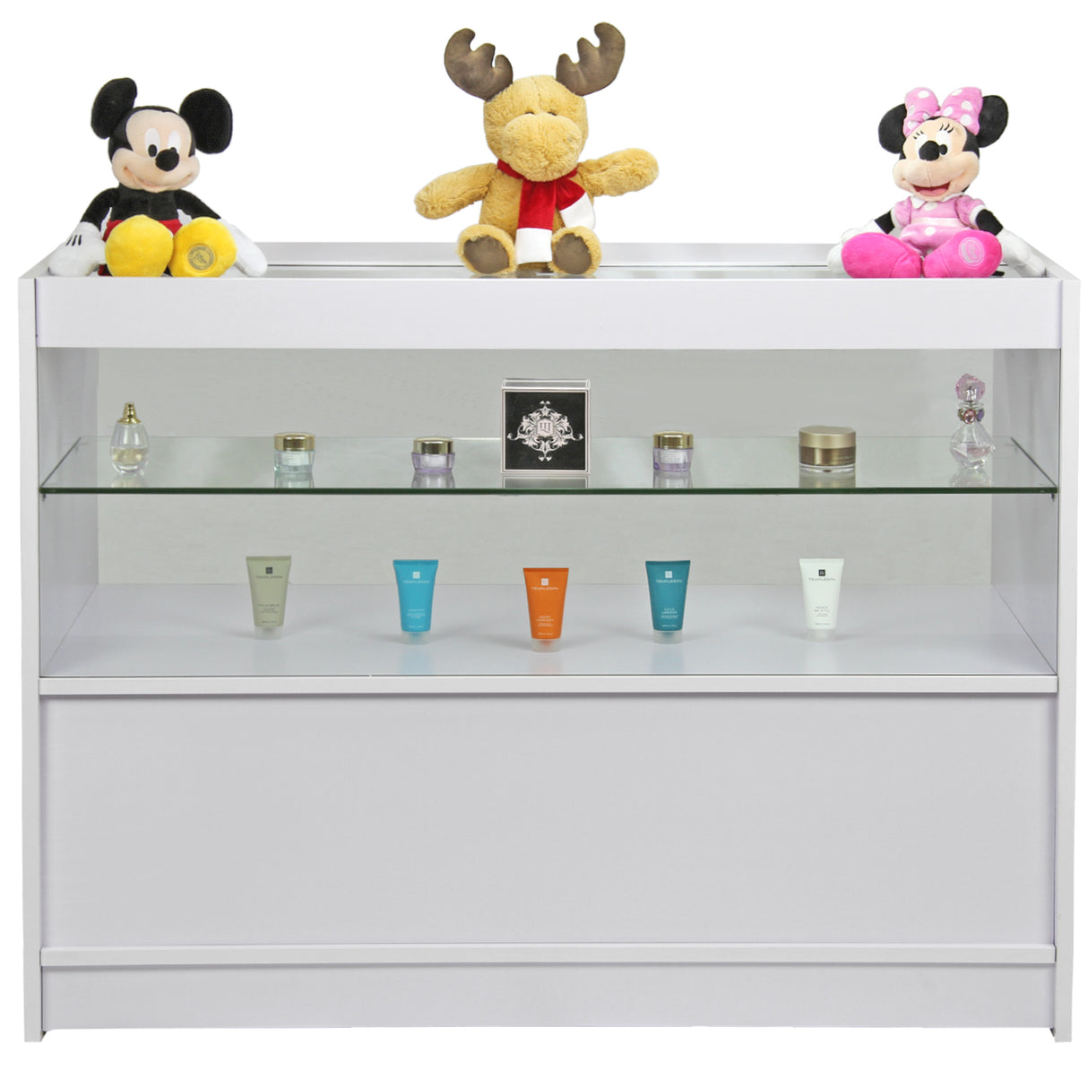Balcão branco brilhante com prateleira de vidro, decorado com pelúcias de Mickey e Minnie, e produtos de beleza coloridos na frente