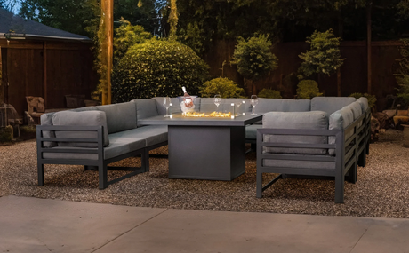 Conjunto de sofá de alumínio cinza com almofadas, mesa central, decorado com velas, em um ambiente externo iluminado e aconchegante