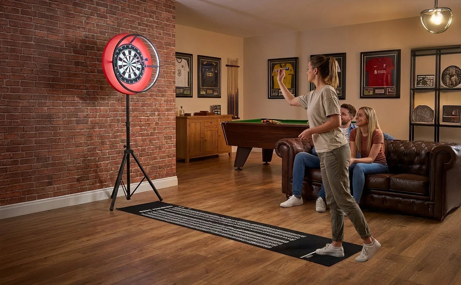 Conjunto de dartboard autônomo em ambiente aconchegante, com parede de tijolos expostos e sofá de couro, pessoas jogando e assistindo