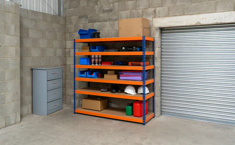 Estante de garagem com prateleiras laranja e azul, organizada com caixas, ferramentas, capacetes e produtos de limpeza, em ambiente de concreto