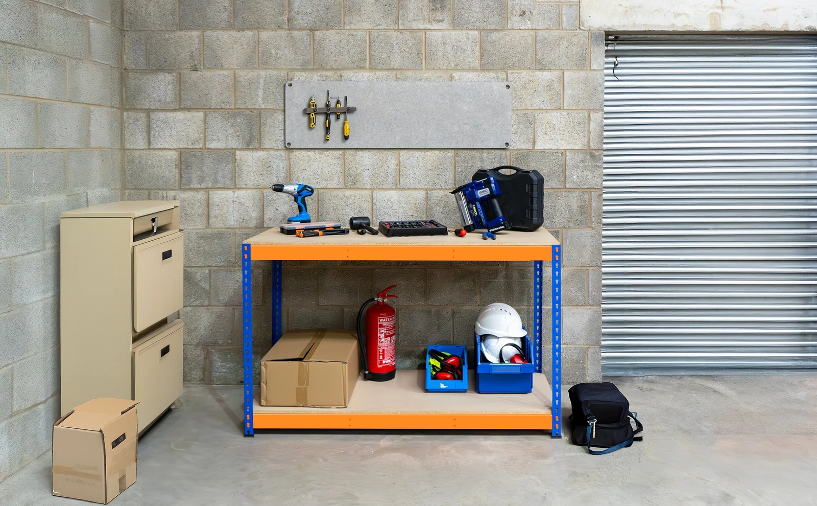 Bancada de trabalho azul com ferramentas, caixa de ferramentas, capacete e extintor, em ambiente de garagem com paredes de bloco de concreto