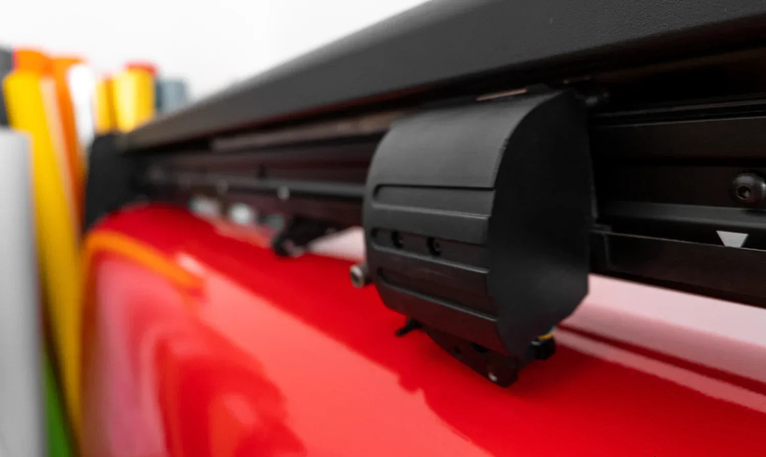 Cortador de vinil vermelho com detalhes em preto, destacando a lâmina e a estrutura para cortes precisos em materiais diversos