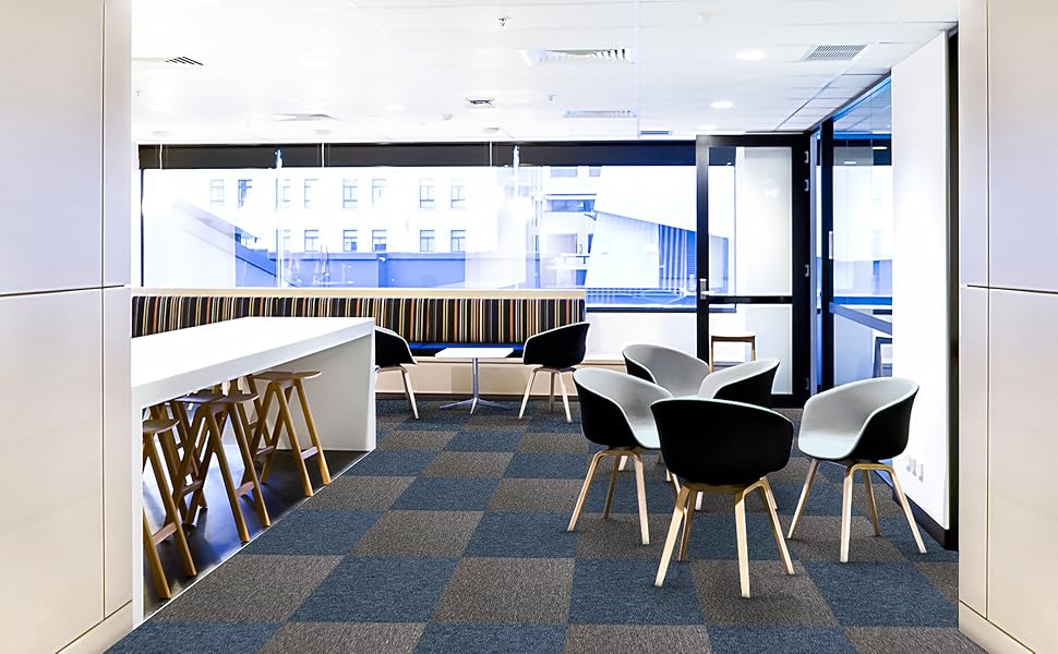 Piso de carpete modular em tons de azul e cinza, com cadeiras modernas em preto e branco, criando um ambiente contemporâneo e acolhedor