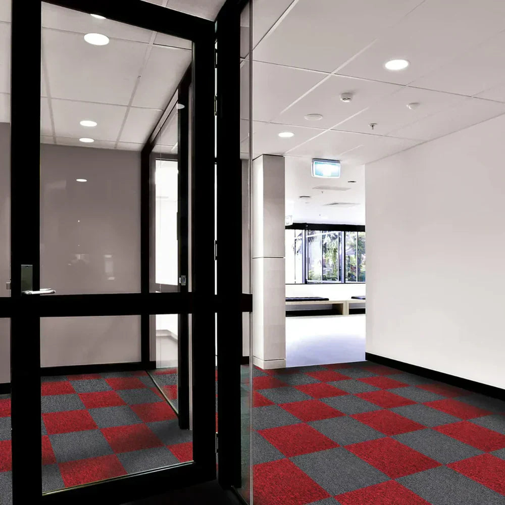 Piso de carpete em quadrados vermelhos e cinzas, com acabamento liso, em um ambiente moderno e bem iluminado, com portas de vidro