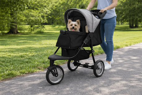 Carrinho de bebê para pets com design moderno, estrutura preta e tecido cinza, transportando um cachorro feliz em um parque verdejante