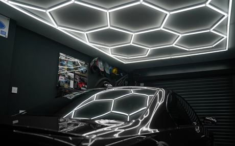 Iluminação LED hexagonal brilhante no teto de uma garagem moderna, refletindo em um carro preto, criando um ambiente elegante e contemporâneo