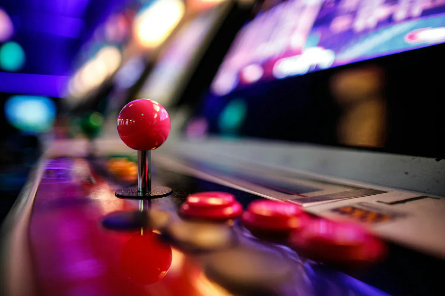 Controle de máquina de arcade com botão rosa brilhante e joystick metálico, em um ambiente iluminado com luzes coloridas e vibrantes