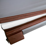 Colchão cinza com borda marrom, textura suave e detalhes em couro, destacando o conforto e a elegância do design moderno