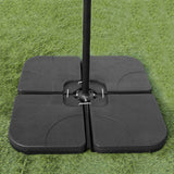 Base preta sólida para guarda-sol, com quatro peças quadradas, ideal para estabilidade em áreas externas, sobre grama verde