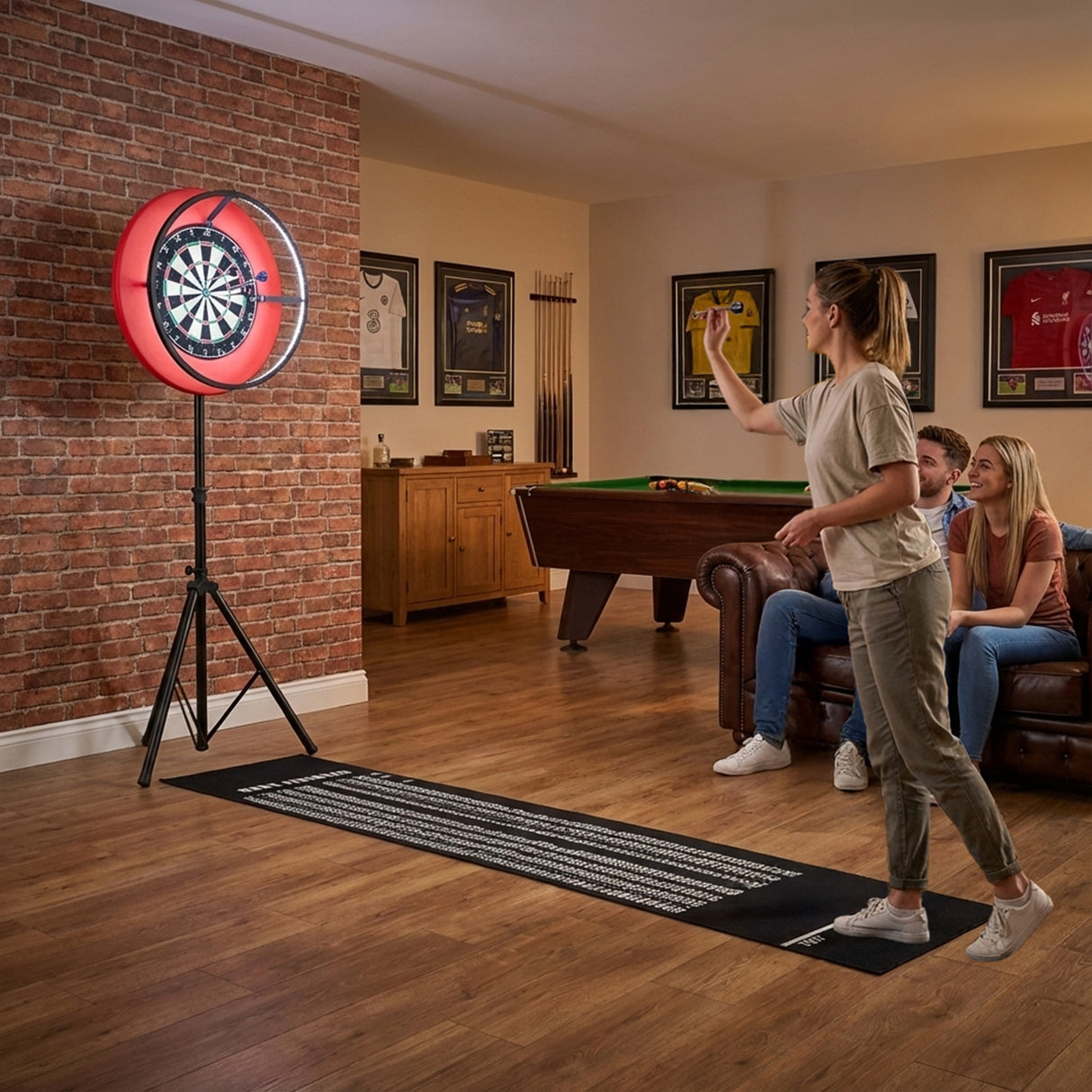 Jogo de dardos com moldura LED em destaque, com luzes vermelhas, em ambiente aconchegante com sofá e mesa de bilhar ao fundo