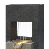 Fonte de água elétrica para jardim "Cascade Springs" em pedra escura, com água jorrando suavemente e luz suave iluminando a base