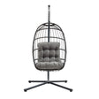Cadeira suspensa tipo ovo em rattan preto, com estrutura metálica e almofada cinza acolchoada, ideal para relaxar e decorar ambientes