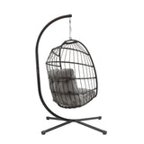 Cadeira suspensa tipo ovo em rattan preto, com estrutura metálica e almofadas cinzas, ideal para relaxar em ambientes internos ou externos