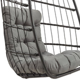 Cadeira suspensa tipo ovo em rattan preto, com almofada cinza acolchoada e estrutura de metal entrelaçada, ideal para relaxar