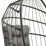 Cadeira suspensa tipo ovo em rattan preto, com estrutura de fios entrelaçados e almofada cinza acolchoada para conforto e estilo