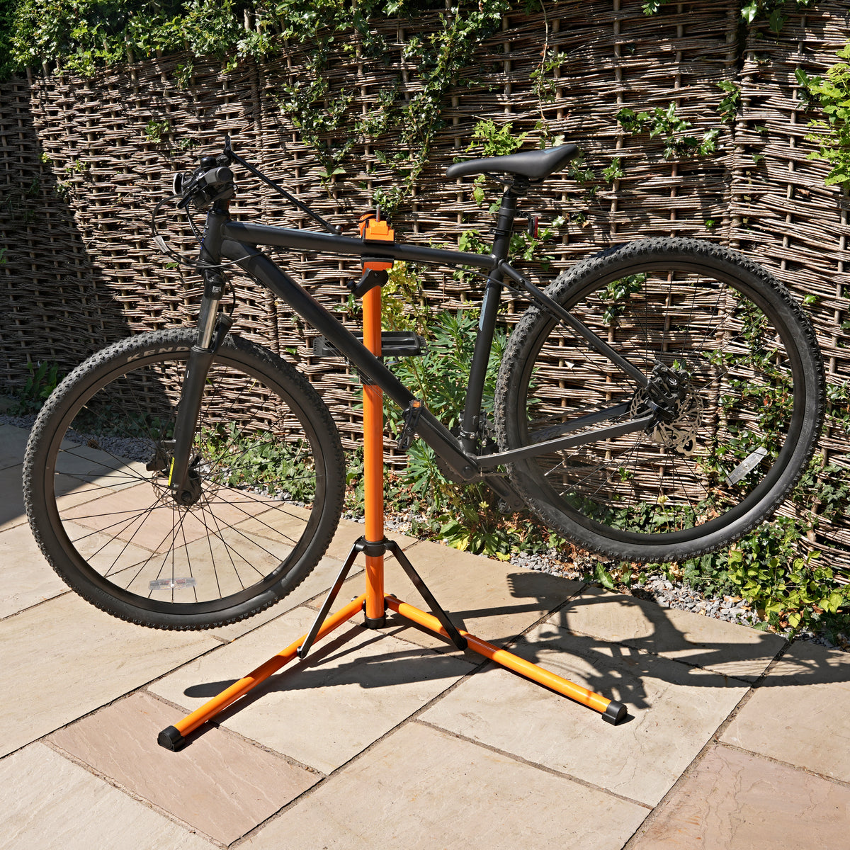 Suporte de oficina para bicicletas em preto e laranja, com estrutura estável e ajustável, ideal para manutenção e reparos