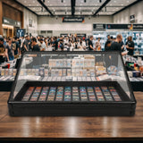 Vitrine de exibição com cartas colecionáveis coloridas, rodeada por uma multidão em um evento de mercado de jogos e colecionáveis