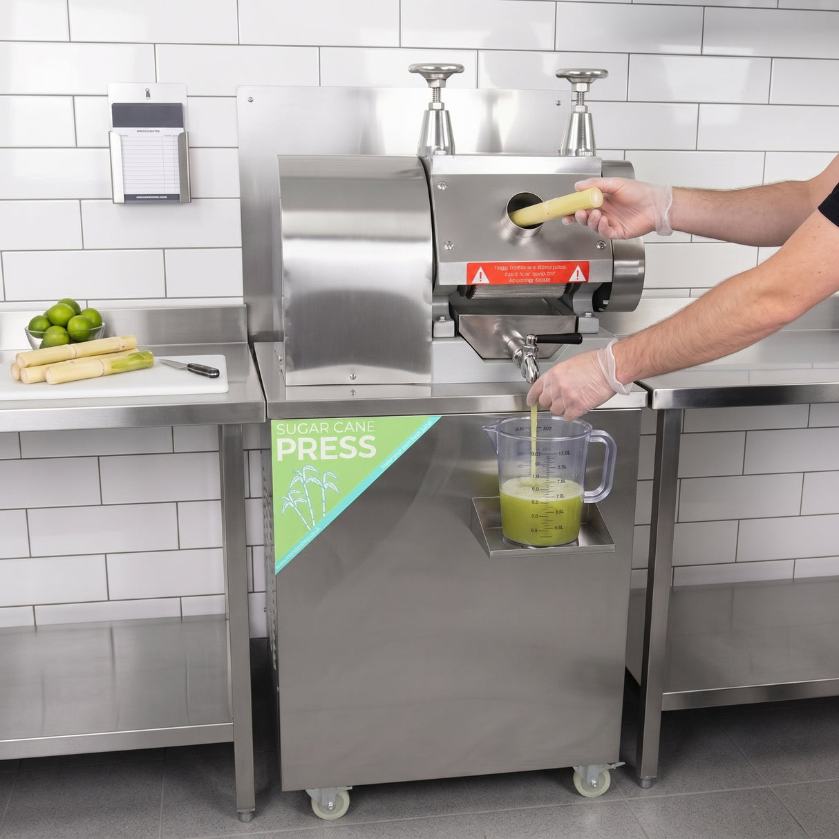 Máquina de suco de cana em aço inox, com alavanca e recipiente transparente coletando suco fresco, em ambiente moderno e limpo