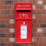 Caixa de correio Royal Mail vermelha com suporte, destacando detalhes em relevo e aviso de horários de coleta em papel branco