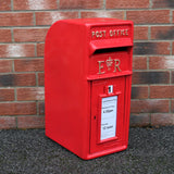 Caixa de correio Royal Mail vermelha com suporte, detalhes em relevo e etiqueta de horário de coleta visível na frente