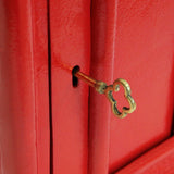 Caixa de correio Royal Mail vermelha com suporte, destacando a textura brilhante e a chave dourada em forma de nuvem