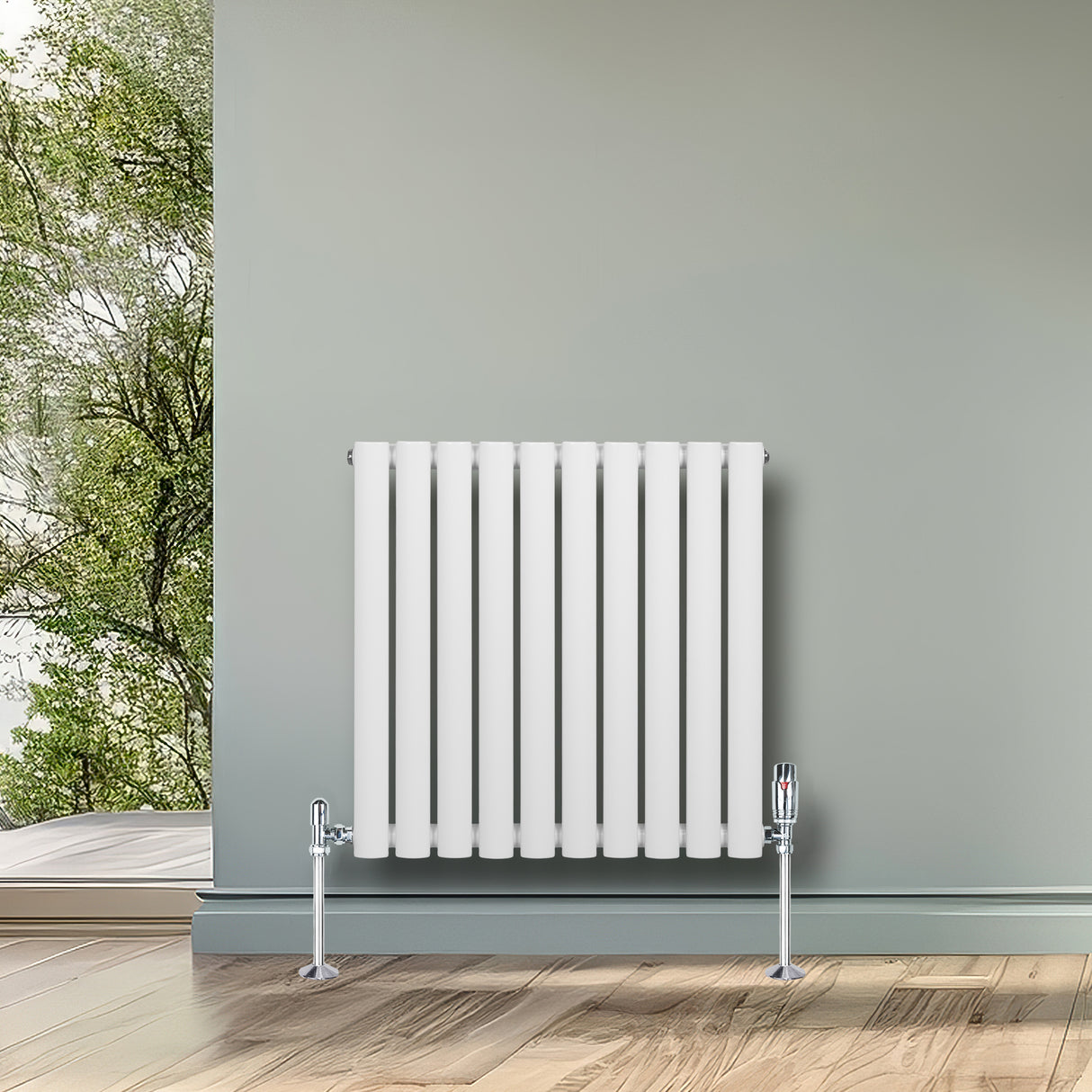 Radiador de coluna oval branco, com válvulas, instalado em parede cinza, destacando-se em ambiente moderno com piso de madeira clara