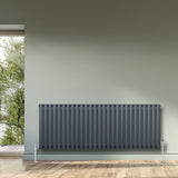 Radiador de coluna oval cinza antracite, 600 mm x 1620 mm, com design liso e moderno, instalado em parede clara com vista externa