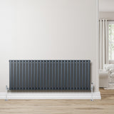 Radiador de coluna oval cinza antracite, com válvulas, instalado em parede clara, destacando seu design moderno e elegante