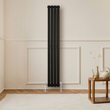 Radiador de coluna oval preto, com design elegante e moderno, instalado em parede clara, destacando suas válvulas cromadas e formato vertical