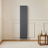 Radiador de coluna simples oval cinza antracite, com design elegante e moderno, instalado em parede clara, ao lado de mesa de madeira