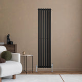 Radiador de coluna simples oval preto, com design elegante e moderno, instalado em parede clara, destacando-se no ambiente aconchegante