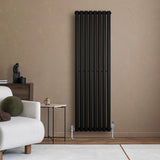 Radiador de coluna simples oval preto, 1600 mm x 480 mm, com válvulas, instalado em parede de tom neutro, ao lado de sofá moderno