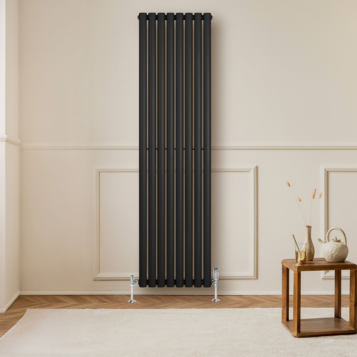Radiador de coluna simples oval preto, com seis tubos verticais, instalado em parede clara, ao lado de mesa de madeira e decoração minimalista
