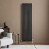 Radiador de coluna simples oval preto, com válvulas, instalado em parede clara, ao lado de sofá e mesa de centro moderna