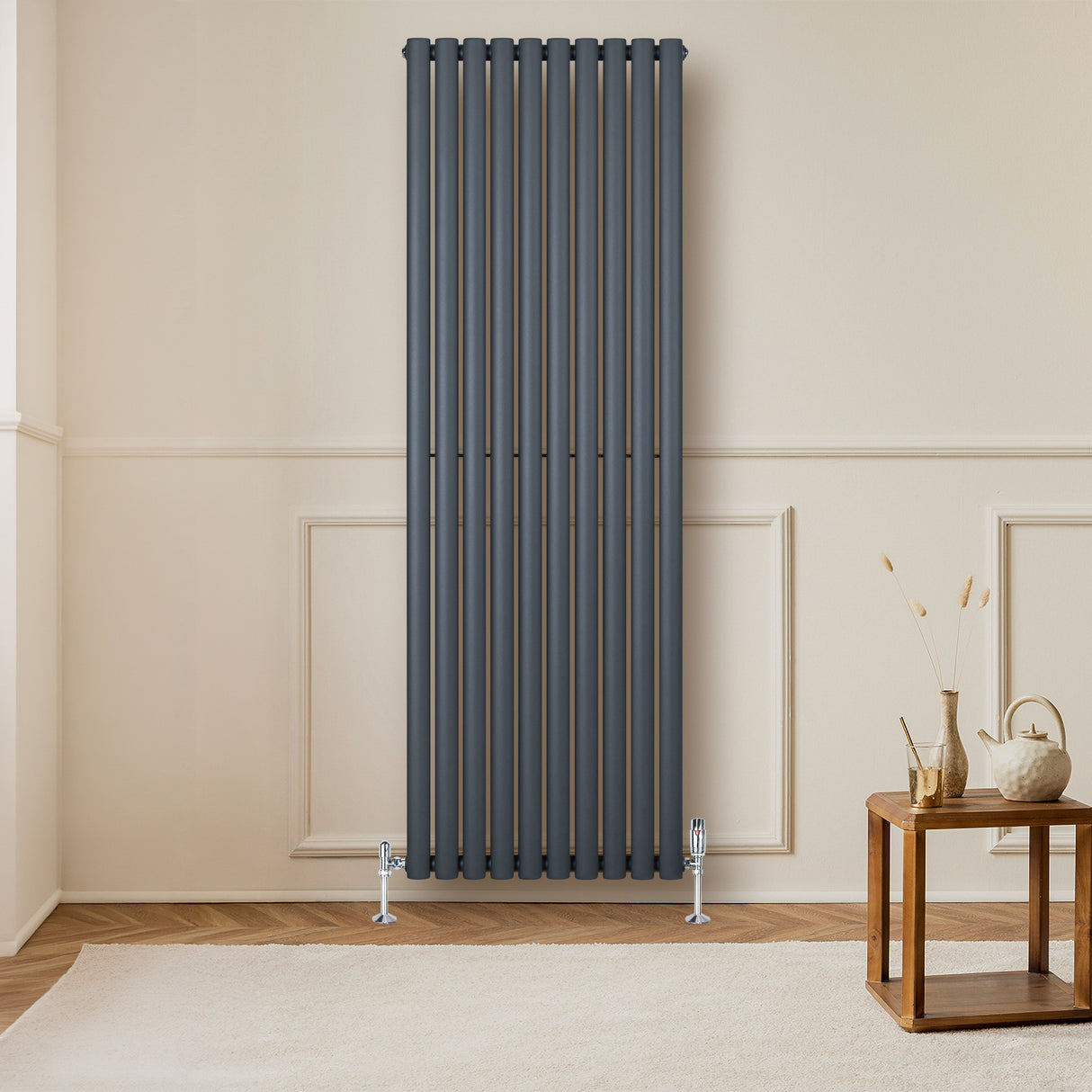 Radiador de coluna oval cinza antracite, com válvulas, instalado em parede clara, destacando seu design moderno e elegante