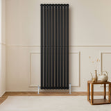 Radiador de coluna simples oval preto, com design elegante e moderno, instalado em parede clara, complementando a decoração do ambiente