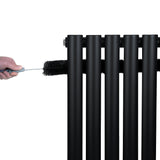 Radiador de coluna oval preto com válvulas, destacando tubos verticais e textura lisa, sendo limpo com escova