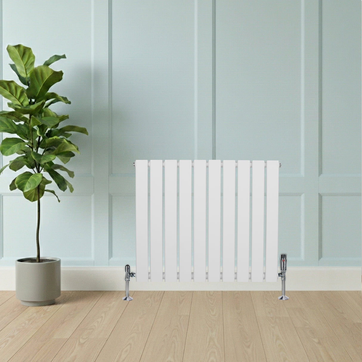 Radiador plano de coluna simples branco com válvulas, instalado em parede clara, ao lado de planta em vaso sobre piso de madeira clara