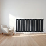 Radiador plano de coluna simples em preto, com design elegante e válvulas, instalado em parede clara ao lado de uma cadeira moderna