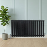 Radiador plano de coluna simples preto, com design elegante e listras verticais, instalado em ambiente moderno com planta ao lado