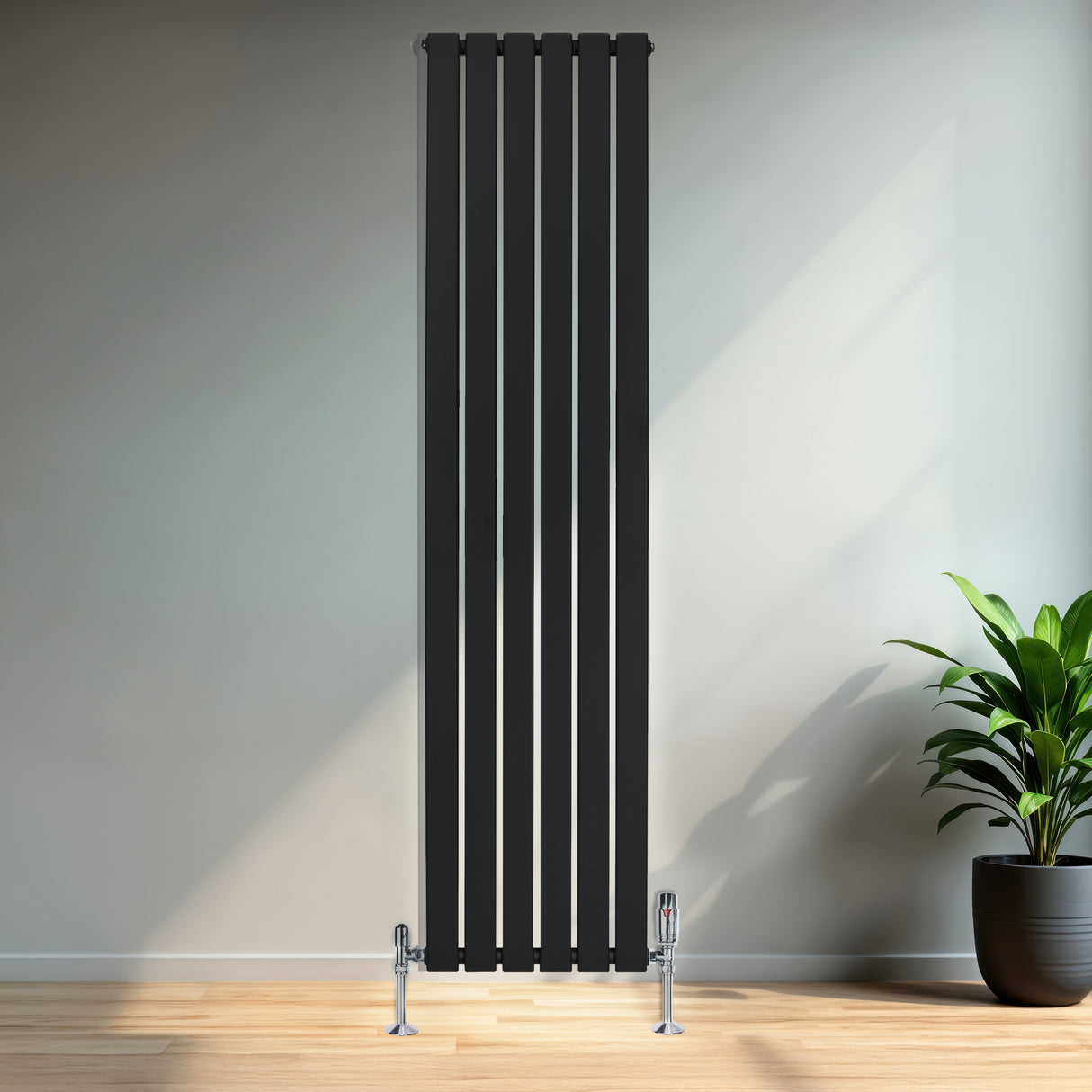 Radiador plano de coluna simples preto, com design vertical e válvulas, instalado em parede clara, ao lado de planta verde em vaso
