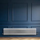 Radiador tradicional de 4 colunas em branco, instalado em parede azul, com válvulas visíveis e textura suave, ideal para aquecimento