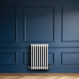 Radiador tradicional branco de 4 colunas, com válvulas, instalado em parede azul, destacando seu design clássico e elegante